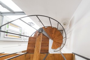 Una scala a chiocciola con finitura in legno e ringhiere in metallo, che conduce a un piano superiore.