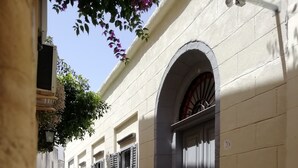 Una calle estrecha con un edificio que tiene un gran arco de entrada y contraventanas.