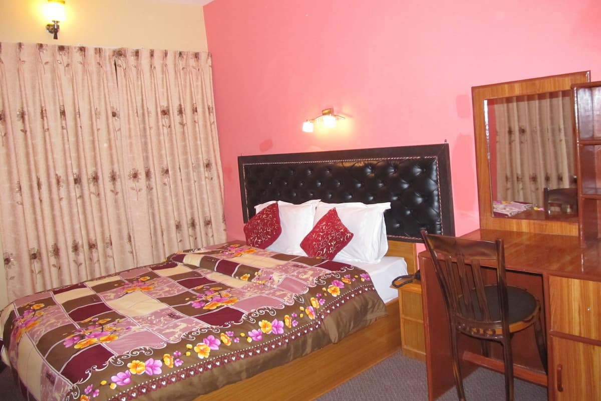 A bedroom with a bed, a desk, and a chair.