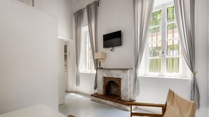 Una habitación con chimenea, televisor montado en la pared y una ventana con cortinas.