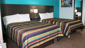 A hotel room with two beds, each with a striped bedspread, a nightstand with a lamp, and a painting on the wall. - Castle Inn (Castleton-on-Hudson)