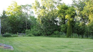 A grassy yard with trees and a wooden deck. - Castle Inn (Castleton-on-Hudson)