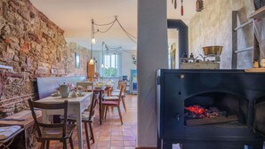A rustic interior with a stone wall, wooden furniture, and a wood-burning stove.