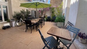 A patio with a table and chairs, a green umbrella, and potted plants. - Large apartment on canal 2 steps from downtown Sète (Sète)