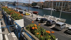 A marina with boats docked, a bridge in the background, and a row of parked cars along the waterfront. - Large apartment on canal 2 steps from downtown Sète (Sète)