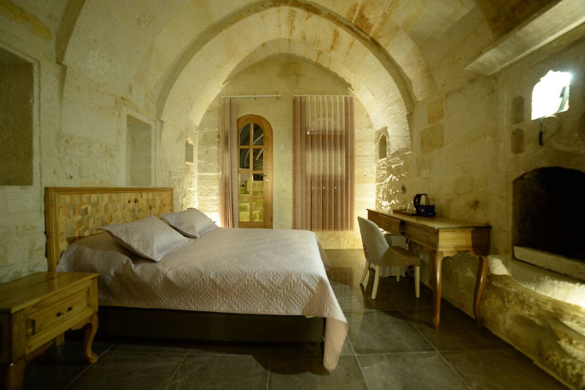 Un dormitorio con cama, escritorio y un arco de entrada.