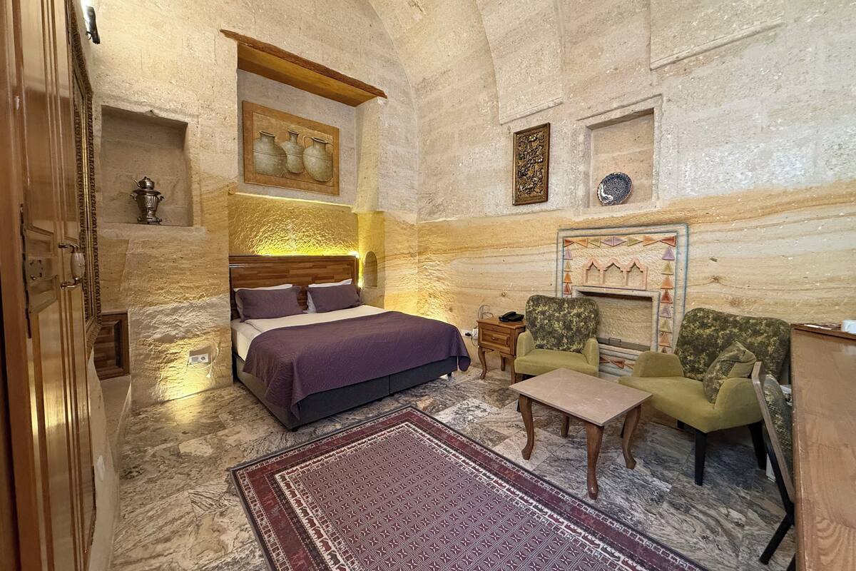 Una habitación con una cama, dos sillones, una mesita y un adorno en la pared.
