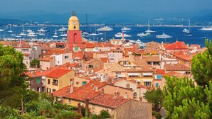 A coastal town with red-tiled rooftops, a prominent yellow and red bell tower, and a marina with numerous boats. - New- Beach 2min, Direct accès marina, 2km from Saint-Tropez (Les marines de Cogolin)
