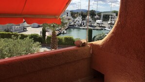 A marina with boats docked, a clear sky, and a red awning over a balcony. - New- Beach 2min, Direct accès marina, 2km from Saint-Tropez (Les marines de Cogolin)