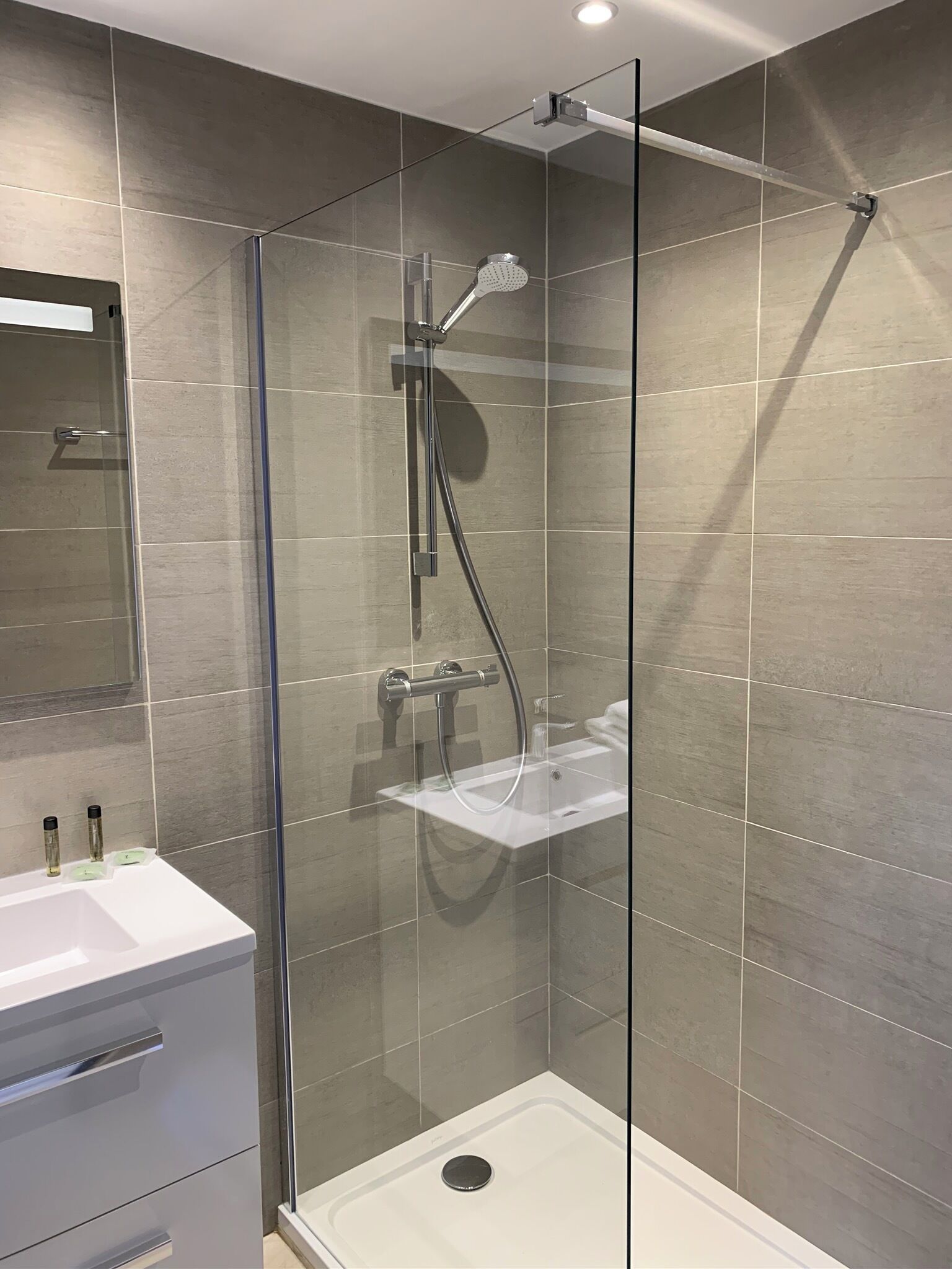 A modern bathroom with a glass-enclosed shower, a white sink, and a mirror above the vanity.