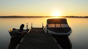 A wooden dock extending into calm water with two boats moored at the end. - Golden Plover's Cabin (Sharbot Lake)