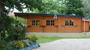 Une cabane en bois avec une cheminée, des fenêtres et une allée gravillonnée.
