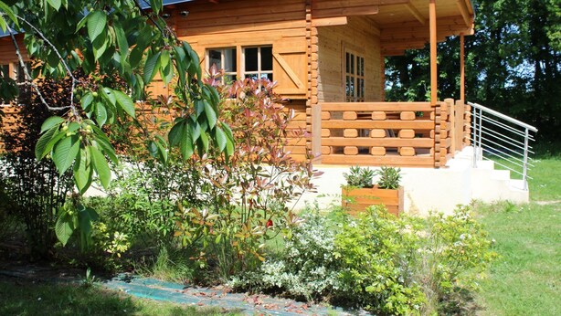 Une cabane en bois dotée d’un porche et d’un escalier menant à une terrasse.