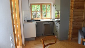 Une cuisine compacte dotée d’une fenêtre, d’un lave-vaisselle et d’un coin repas avec une table et des chaises.