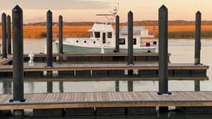 Eine Anlegestelle mit einem Boot, das am Ende vertäut ist, umgeben von hohen Pfählen und ruhigem Wasser.