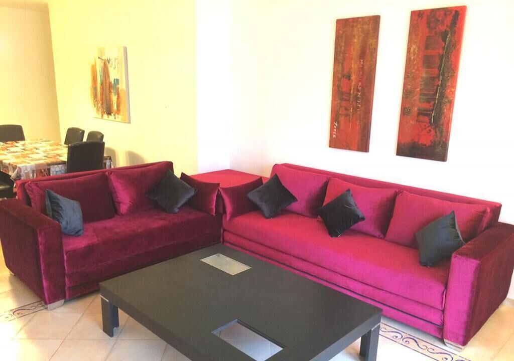 A living room with a red sofa, a coffee table, and two abstract paintings on the wall.