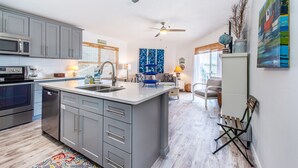 Una cocina moderna con armarios grises, una isla central y un comedor con sofá y mesa.