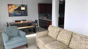A living room with a sofa and a chair, a dining table with chairs, and a kitchen area in the background. - Calabash Villas on Bonaire Bay (Gros Islet)