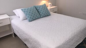 A neatly made bed with a white bedspread and two pillows, one plain and one with a blue pattern. - Calabash Villas on Bonaire Bay (Gros Islet)