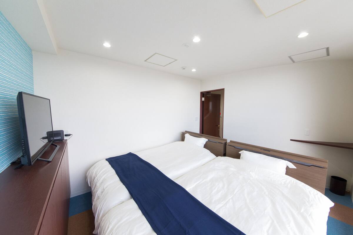 Una habitación de hotel con una cama grande, un escritorio con computadora, un espejo y una puerta.