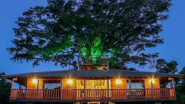 A two-story wooden cabin with a balcony, surrounded by trees. - Pousada Água dos Canyons (Praia Grande)