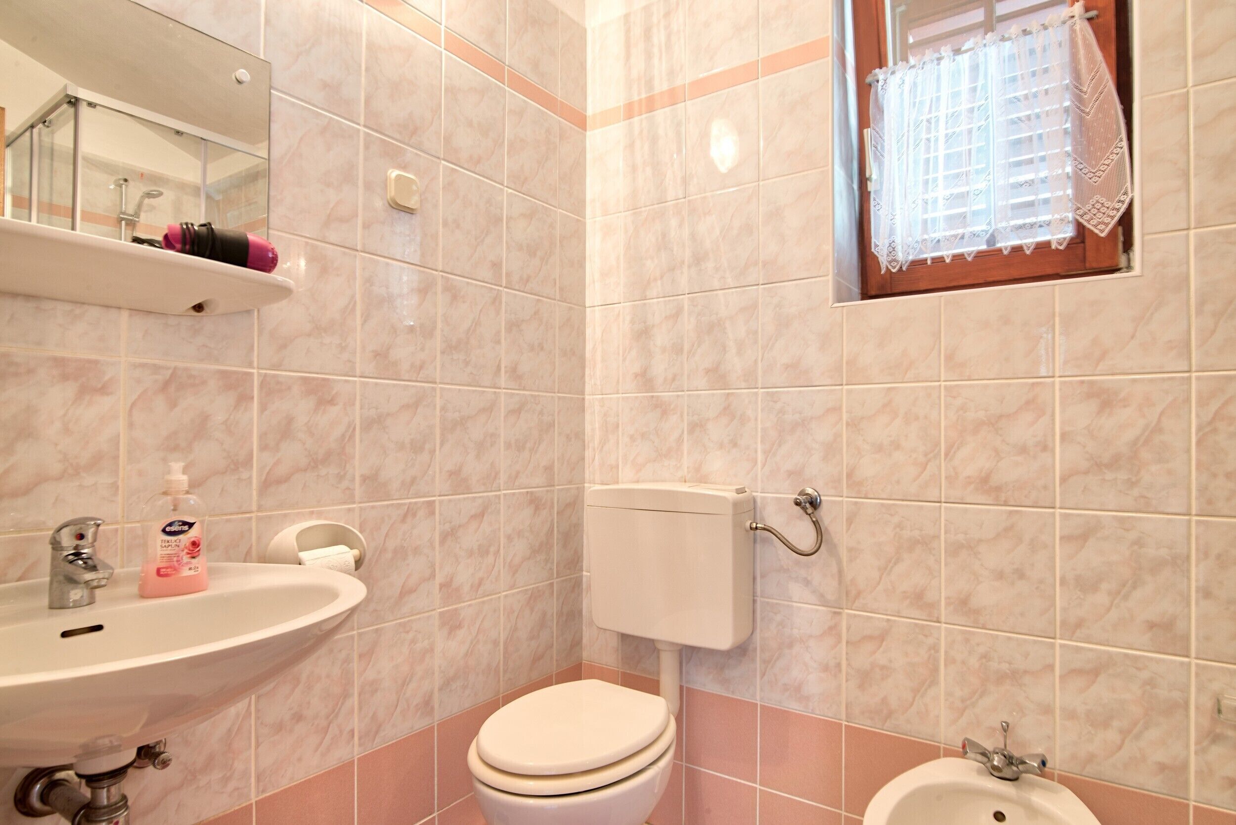 A bathroom with a toilet, sink, and mirror.