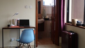 Pieni huone, jossa on työpöytä, tuoli, kannettava tietokone ja ikkuna, jossa on verhot.