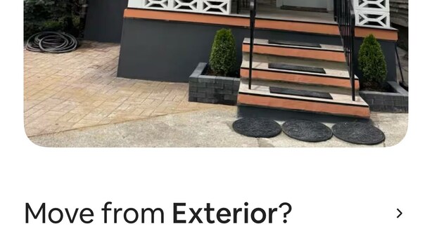 Een tweelaags huis met een veranda, een schotelantenne en een brievenbus.
