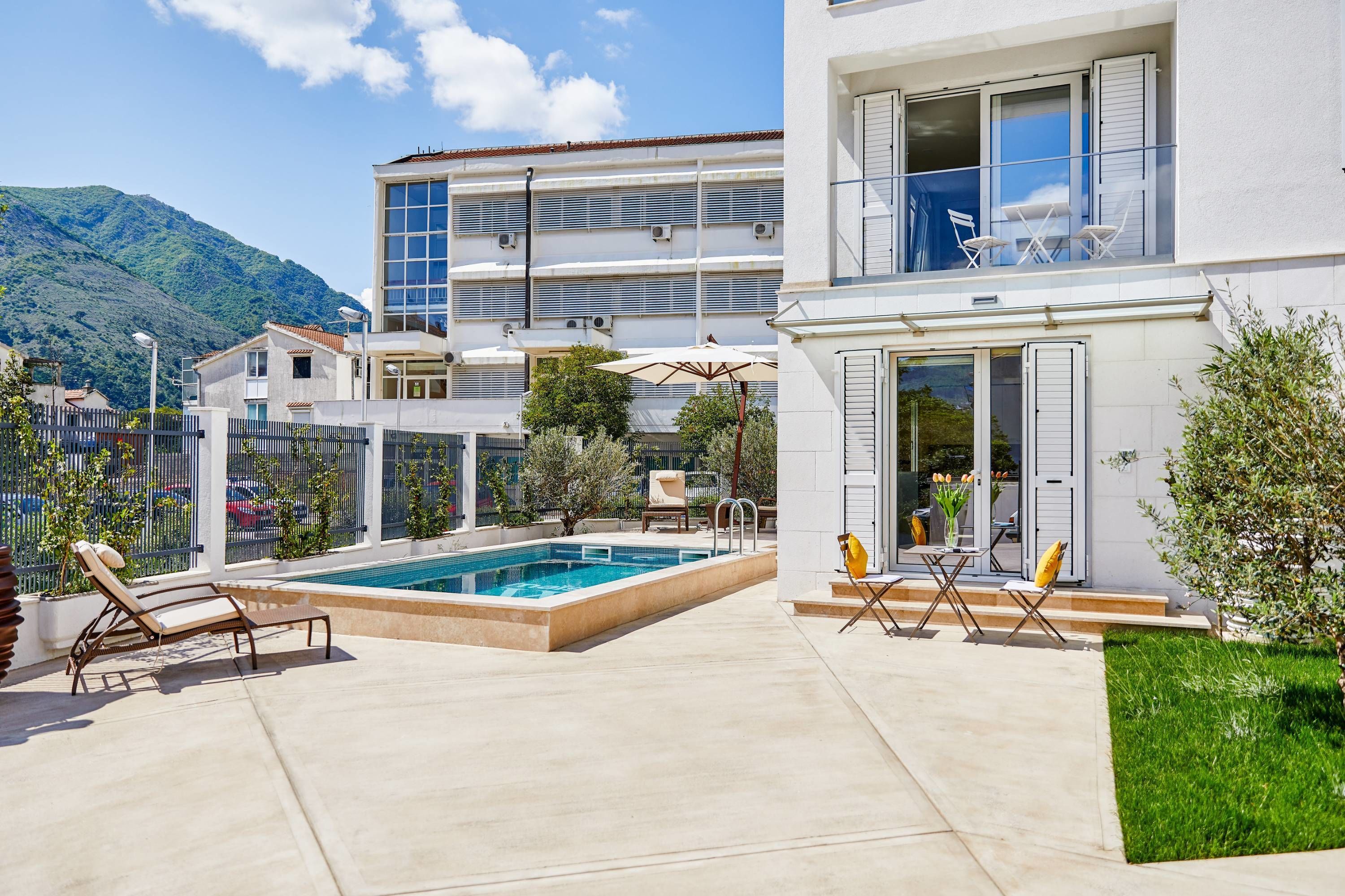 A modern building with a swimming pool, outdoor seating, and a view of a mountain.