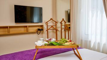 A hotel room with a bed, a tray with snacks, a TV, and a mirror.