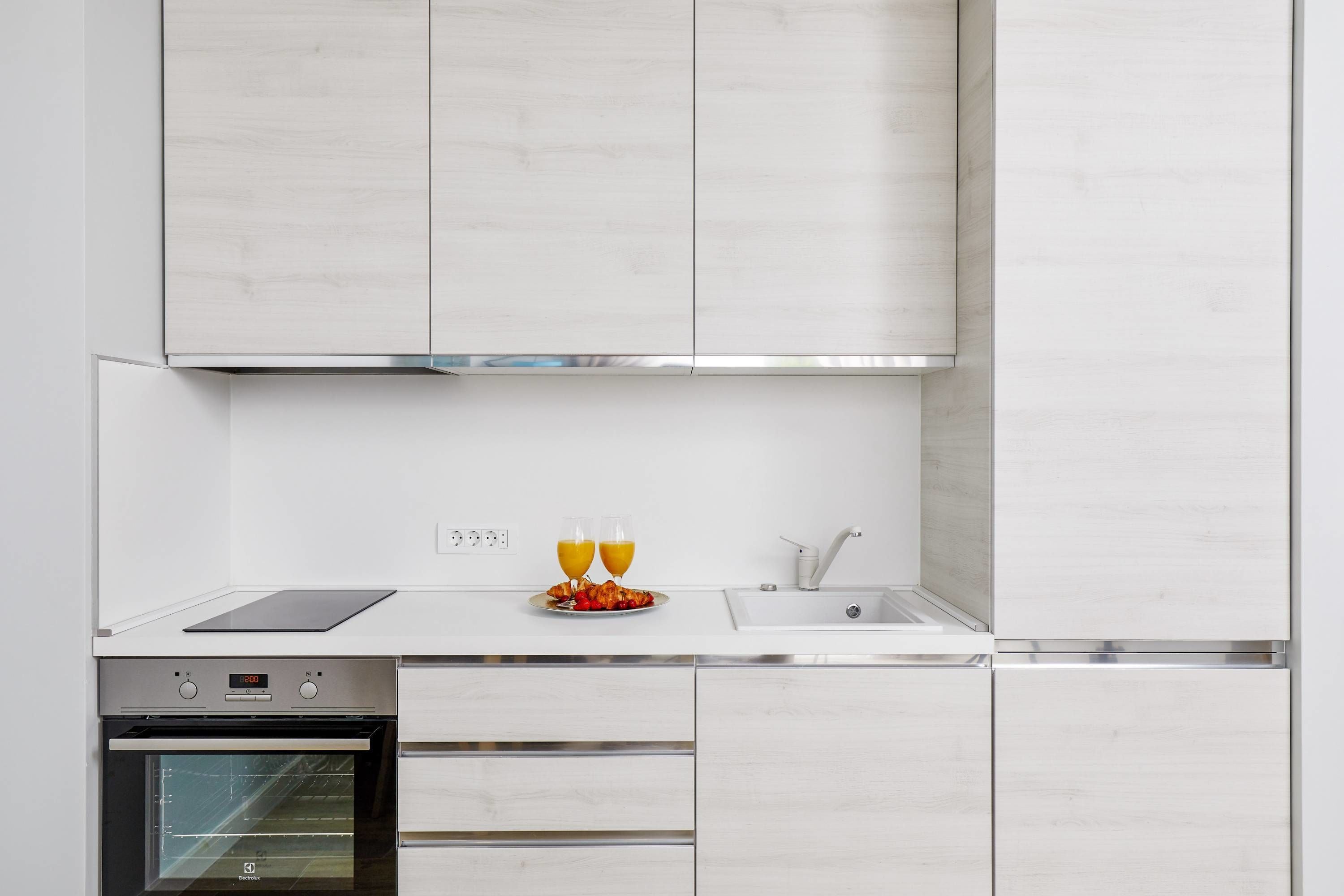 Una cocina moderna con armarios blancos, un horno de acero inoxidable y un reloj digital que muestra las 8:00.