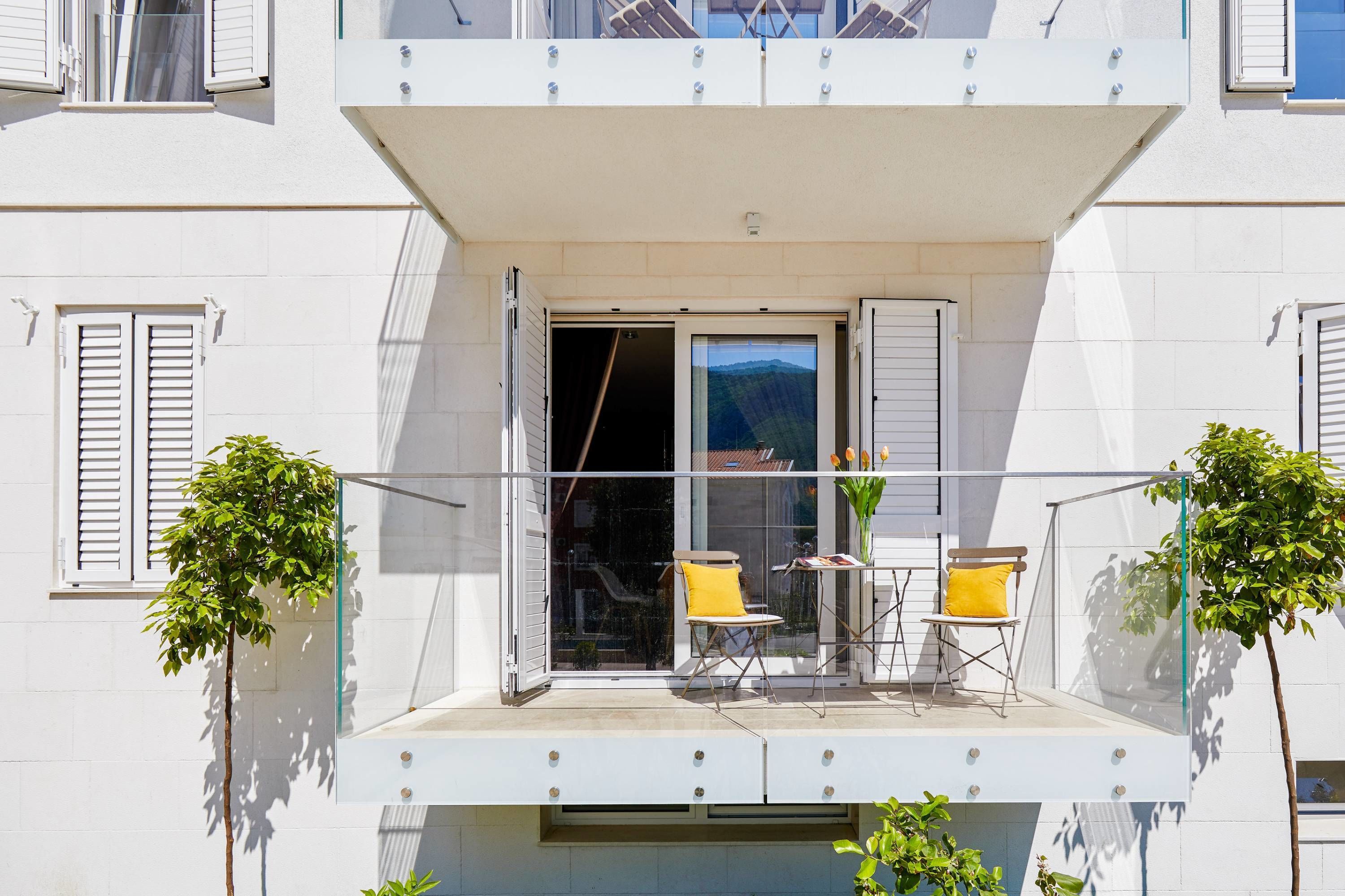 En moderne bygning med en balkon, der har to gule stole og et bord.