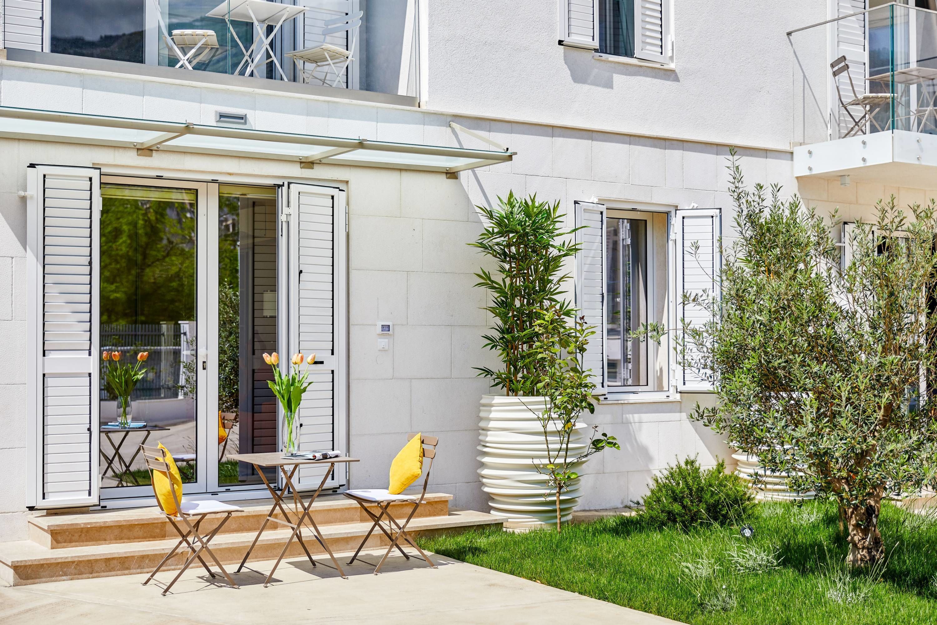 A modern house with a patio, outdoor seating, and a large potted plant.