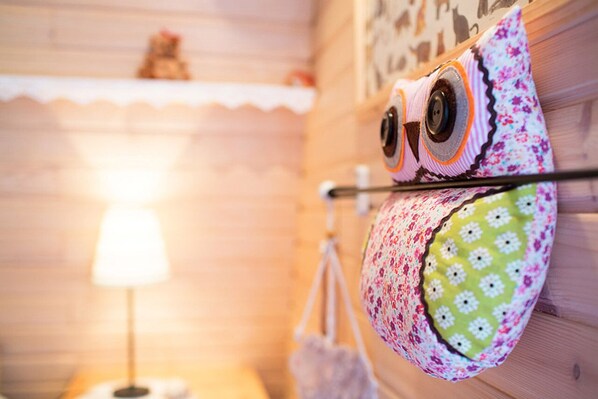 A wall-mounted shelf with a decorative item resembling an owl, a lamp, and a hanging bag.