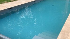 Una piscina con agua azul cristalina y un borde con baldosas.