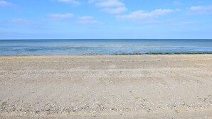 Una playa con cielo despejado y mar tranquilo.