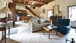 Un salón espacioso con techos altos, una escalera que sube a un nivel superior, un comedor y una cocina.