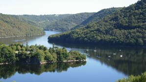 A serene lake surrounded by lush green hills, with several boats anchored near the shore.