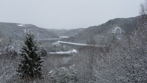 A snowy landscape with a river and a bridge.