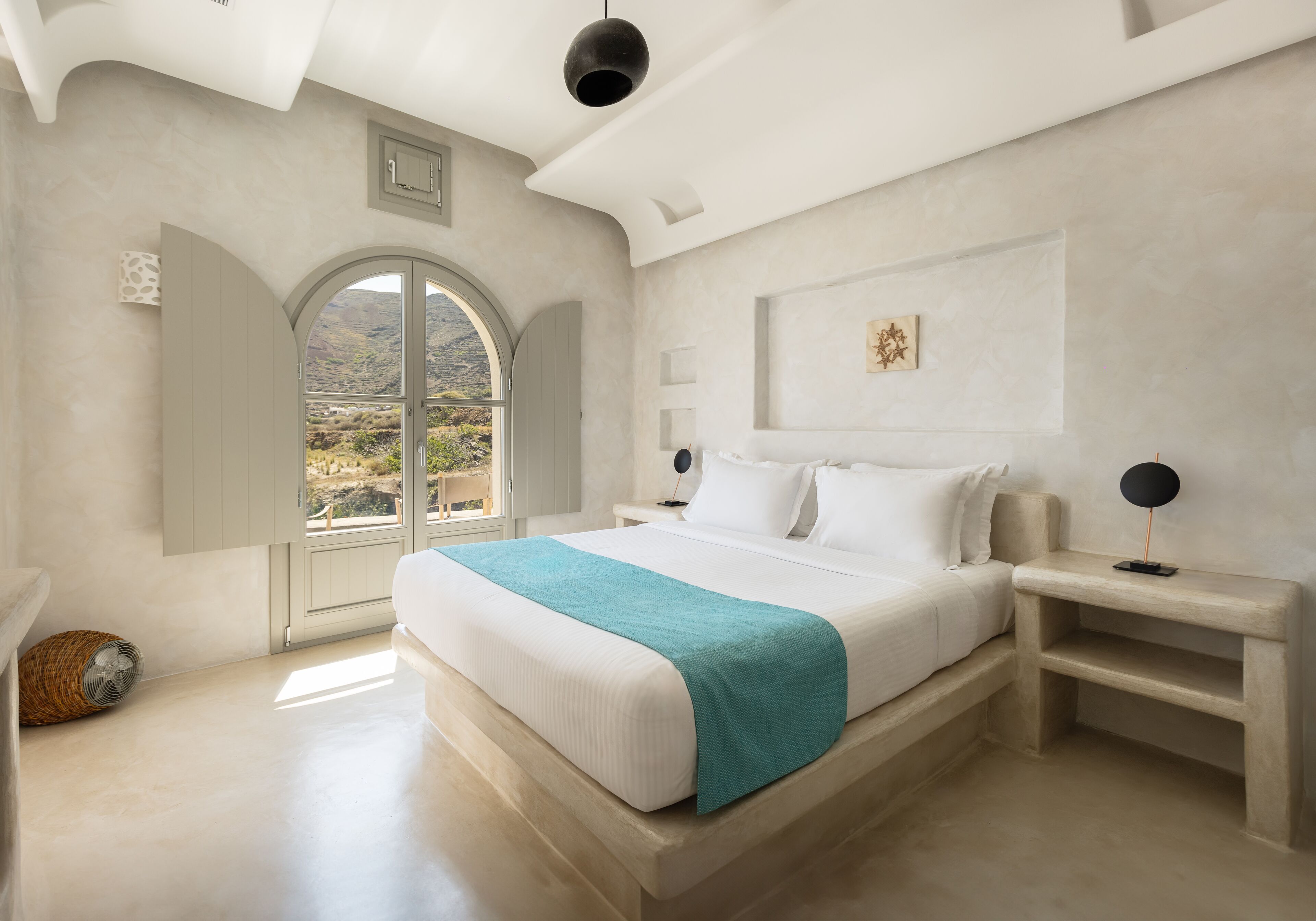 Un dormitorio amplio con una cama grande, vistas al exterior a través de una ventana y un diseño moderno en el techo.