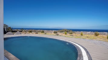 En swimmingpool med utsikt över havet och avlägsna berg.