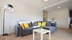 En moderne stue med en grå hjørnesofa, et hvidt sofabord og en gulvlampe.