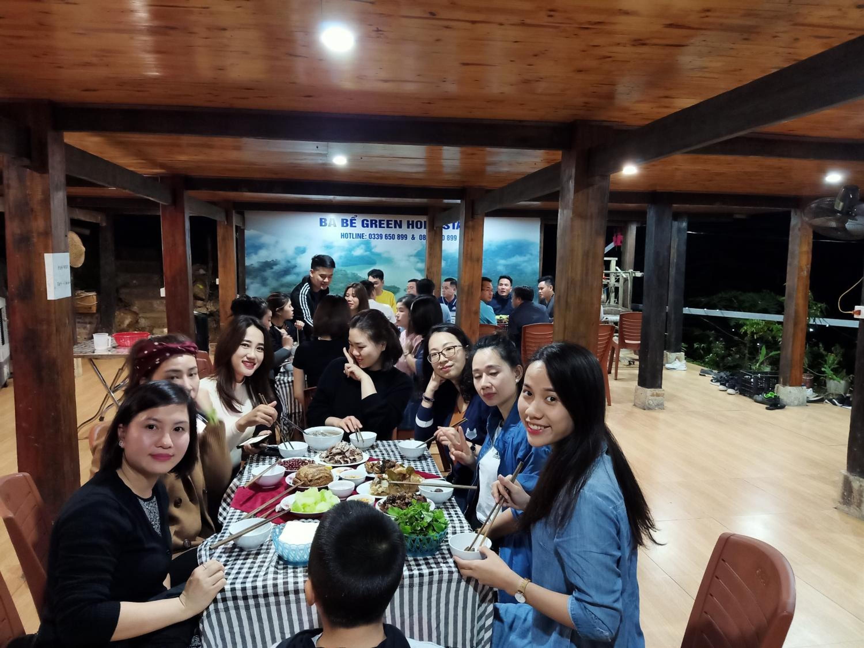 A group of people dining at a restaurant with a wooden interior and a banner in the background.