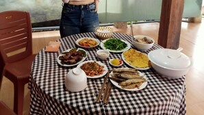 A table with various dishes, a person standing behind it, and a sign in the background.