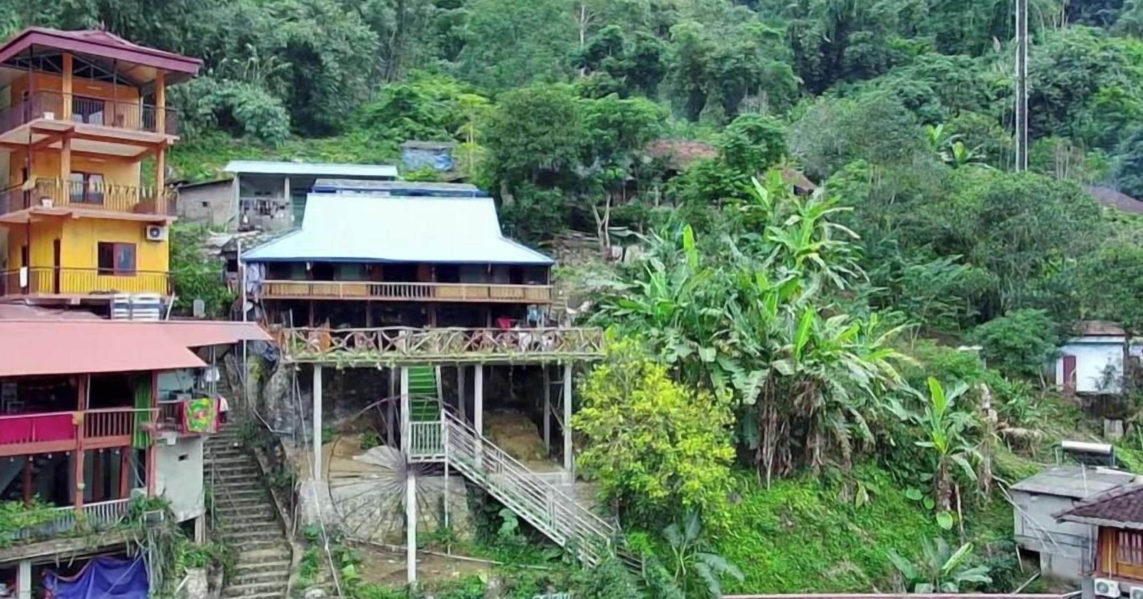 Ein mehrstöckiges Gebäude mit Balkon, umgeben von üppigem Grün.