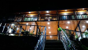 A multi-level building with outdoor stairs, metal railings, and string lights.