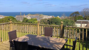 A wooden deck with a table and chairs overlooking a coastal town.