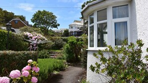 A garden pathway leading to a house with a bay window.