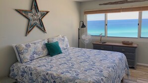 Une chambre à coucher avec un lit, une décoration en forme d’étoile, une table de chevet, une lampe et une vue sur l’océan.