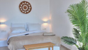 Een slaapkamer met een bed, bedlampen, een wanddecoratie en een plant in een pot.